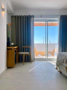 a bedroom with a window with a view of the ocean at Calistus Mykonos in Mikonos