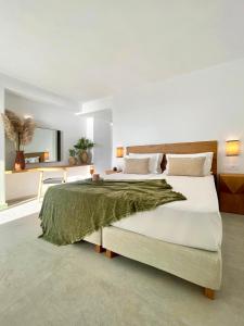 a bedroom with a large bed with a green blanket on it at Calistus Mykonos in Mikonos