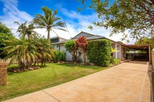 a house with palm trees and a driveway at Sunbaker Pet Friendly Awards Finalist 4 Mins Walk to Culburra Beach in Culburra Beach
