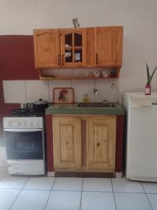 cocina con armarios de madera y nevera blanca en La posada del sol en Posadas