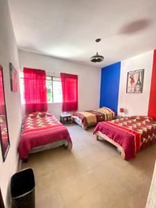 a bedroom with two beds and red curtains at Casa Alsacia in Guadalajara