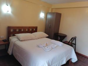 Un dormitorio con una cama blanca con toallas. en Suyay B&B, en Cusco