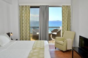 ein Schlafzimmer mit einem Bett und einem Stuhl sowie einem Balkon in der Unterkunft Limira Mare Hotel in Neapolis