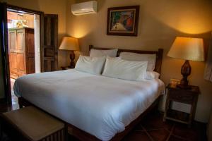 a bedroom with a large white bed with two lamps at Nirvana Restaurant & Retreat in San Miguel de Allende