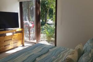 a bedroom with a bed and a tv and a window at TAO Garden Luxury Condo in Akumal