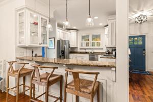 eine Küche mit weißen Schränken und Barhockern in der Unterkunft Heron Cottage - 309 Kelsall Ave in Kings Terrace