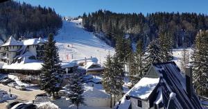 a snow covered resort with a ski slope and trees at Olimpijska kuća A307 in Jahorina