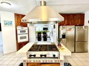 a kitchen with a stove and a stainless steel refrigerator at Casa con Piscina Cerca de playa in Nuevo Vallarta