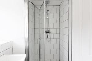 a shower in a bathroom with white tiles at Stable Cottage in Whitby