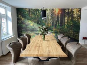 a dining room with a wooden table and a forest mural at Ferienhaus Harzcolor Wernigerode in Wernigerode