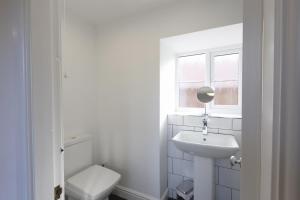 a white bathroom with a toilet and a sink at Stable Cottage in Whitby