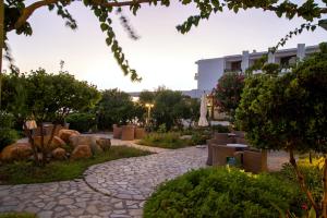 a walkway in a garden with a building in the background at Limira Mare Hotel in Neapoli Voion