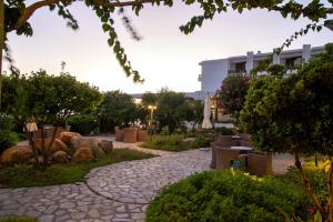 una pasarela en un jardín con un edificio en el fondo en Limira Mare Hotel, en Neápolis