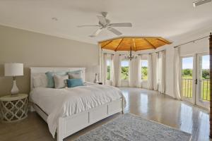 um quarto branco com uma cama e uma ventoinha de tecto em Enchanted Hideaway - 1709 Dixon Lane em Saint Simons Island