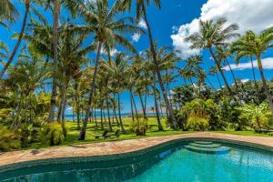 una piscina con palmeras y el océano en el fondo en Halama Hale Private Home home, en Kihei