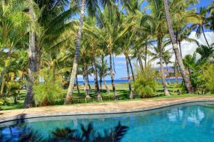 una piscina con palmeras y el océano en Halama Hale Private Home home, en Kihei