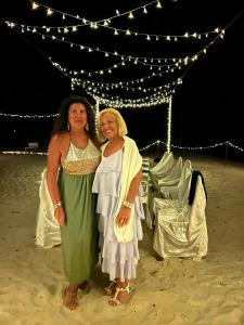 Hangnaameedhoo的住宿－BY THE SHADE，两名妇女站在海滩上帐篷前