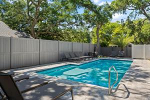 a swimming pool with chairs and a fence at Viewpoint Oaks - 301 7th Street, Unit 101 in Saint Simons