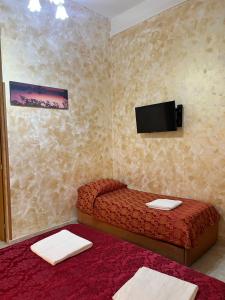 a small room with a bed and a flat screen tv at Rose Village Guest House in Rome