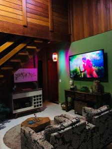 a living room with couches and a flat screen tv at Chalé Vale da Mata - São Roque SP in São Roque