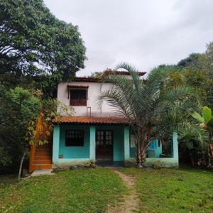 a house with a palm tree in front of it at Casa Quaresmeira in Palmeiras