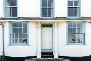 ein weißes Haus mit blauen Fenstern und einer weißen Tür in der Unterkunft Coral in Brixham