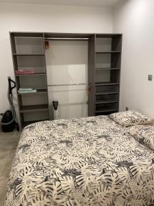 Schlafzimmer mit einem Bett mit einer Bettdecke und Regalen in der Unterkunft Appartement T2 Bayonne st esprit avec parking in Bayonne