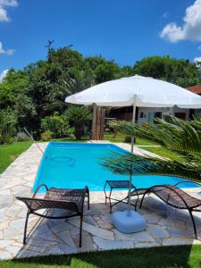 奧蘭布拉的住宿－POUSADA Chacara ENTRE NÓS，一个带两把椅子和一把遮阳伞的游泳池