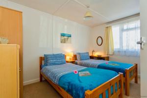 two beds in a small room with blue sheets at CROYDE SEA BREEZE 3 Bedrooms in Croyde