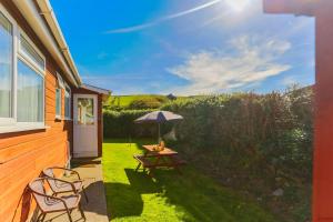 a patio with a table and chairs and an umbrella at CROYDE SEA BREEZE 3 Bedrooms in Croyde