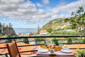 a table with food on a balcony with the ocean at Lidia's Place, a Home in Madeira in Ponta do Sol