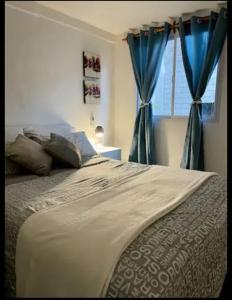 1 dormitorio con 1 cama con cortinas azules y ventana en Departamento El Portal - San Rafael en San Rafael