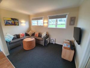 a living room with a couch and a tv at Stanmore Bay Beachfront Cottage in Whangaparaoa