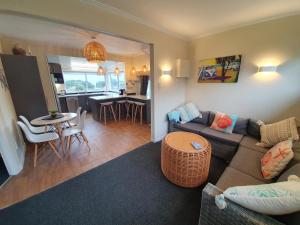 a living room with a couch and a table at Stanmore Bay Beachfront Cottage in Whangaparaoa