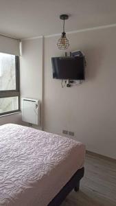 a bedroom with a bed and a tv on the wall at Cercano Estadio Nacional y Plaza Ñuñoa in Santiago