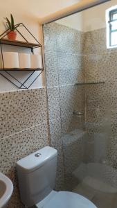 a bathroom with a toilet and a glass shower at Casa Quaresmeira in Palmeiras