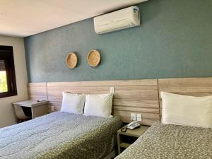 トーレスにあるAruá Pousada Boutiqueのベッド2台、壁にエアコンが備わるホテルルームです。