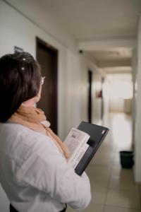 a woman standing in a hallway holding a book at OK Inn Hotel Criciúma in Criciúma