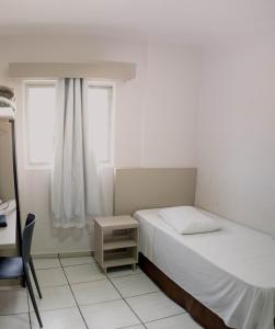 a bedroom with a bed and a desk and a window at OK Inn Hotel Criciúma in Criciúma