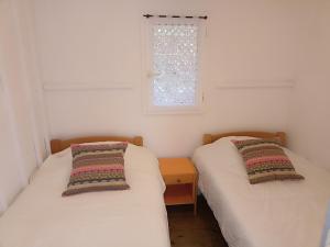 2 Einzelbetten in einem Zimmer mit Fenster in der Unterkunft Les cabanes de l'île aux oiseaux Guern in Guern