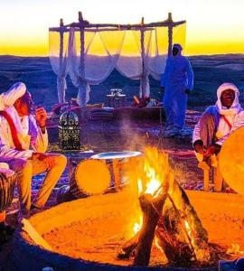 メルズーガにあるMerzouga Stars Campの火の周りに座る人々