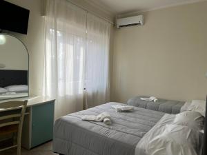 1 Schlafzimmer mit 2 Betten, einem Schreibtisch und einem Spiegel in der Unterkunft R&B Hotel in Alfonsine