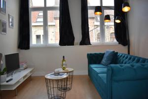 sala de estar con sofá azul y 2 ventanas en Gastenverblijf De Arend en Nieuwpoort