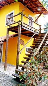 a yellow house with a wooden staircase in front of it at Casa temporada na praia Joia do Atlântico - Ilhéus - Ba in Ilhéus
