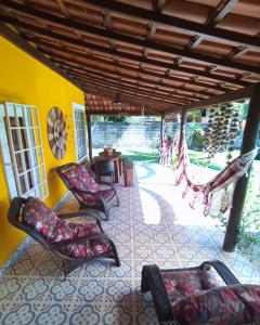 a porch with chairs and a table and a hammock at Casa temporada na praia Joia do Atlântico - Ilhéus - Ba in Ilhéus