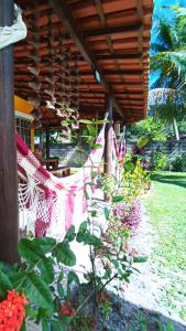 a hammock is hanging under a house with flowers at Casa temporada na praia Joia do Atlântico - Ilhéus - Ba in Ilhéus