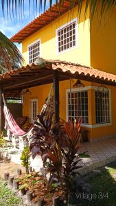 a yellow house with a hammock in front of it at Casa temporada na praia Joia do Atlântico - Ilhéus - Ba in Ilhéus