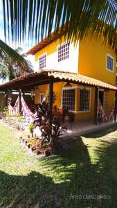 a yellow and white house with a palm tree at Casa temporada na praia Joia do Atlântico - Ilhéus - Ba in Ilhéus