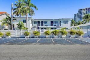 einen weißen Zaun mit Palmen auf einem Parkplatz in der Unterkunft Waves On Desoto 1- Bedroom Rental Unit With Pool in Hollywood