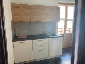 a kitchen with white cabinets and a sink at Appartamento Eleonora in Vermiglio